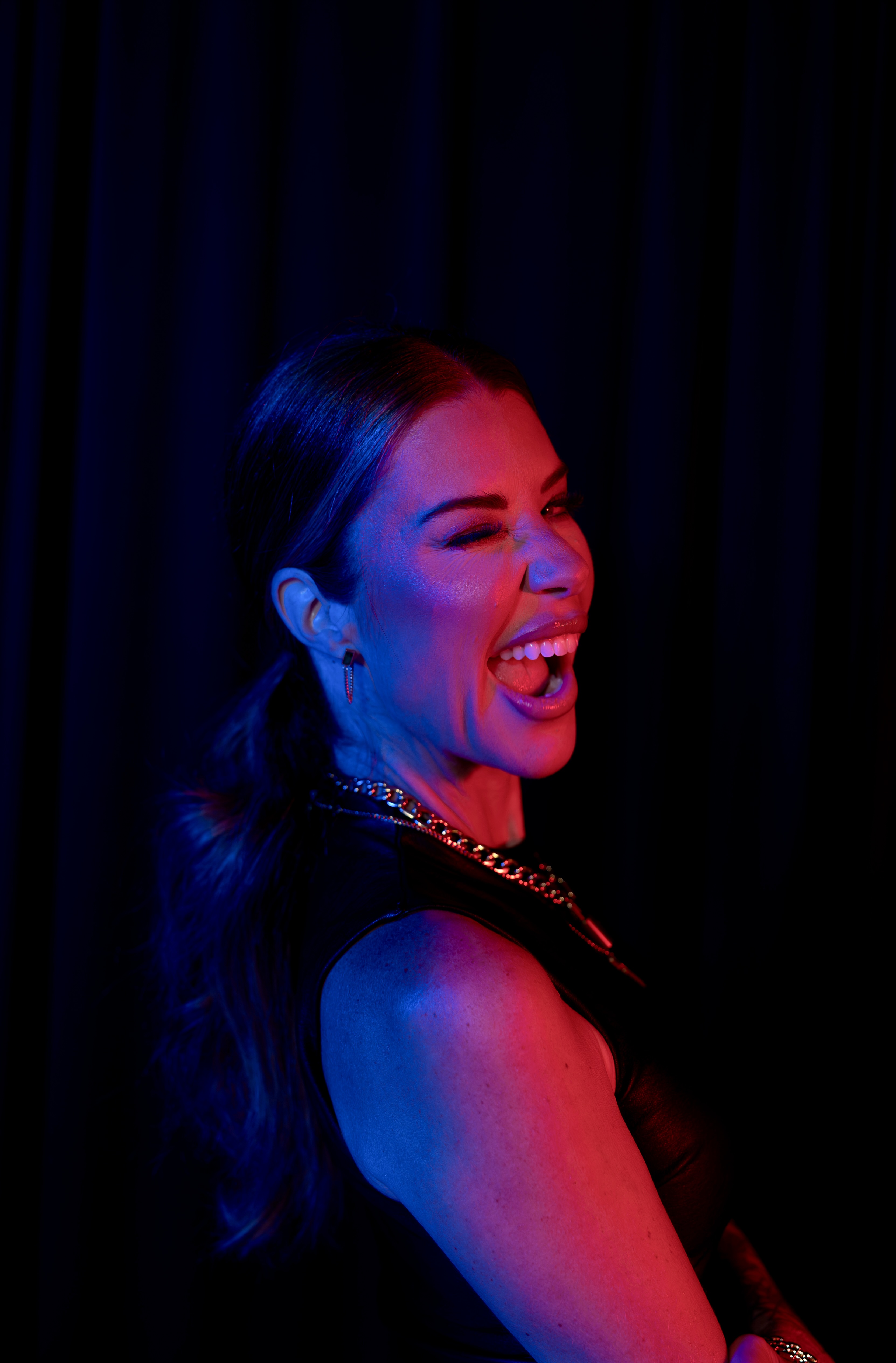 Ashley Tomblin laughing in profile under stage lighting.